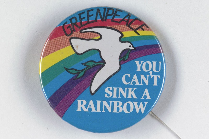 Blue-coloured badge with a rainbow and white dove on it. Text reads “Greenpeace” and “You can’t sink a rainbow”