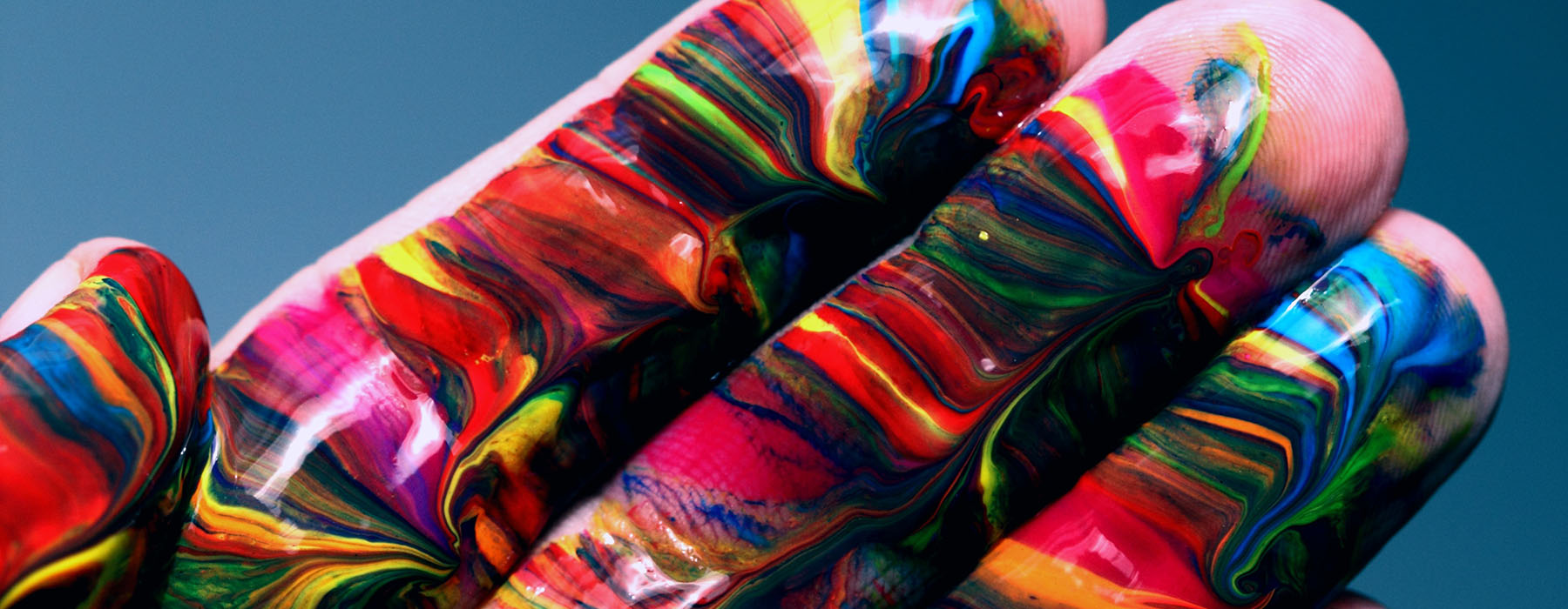 Close-up photo of a hand with multicoloured paints smeared across it