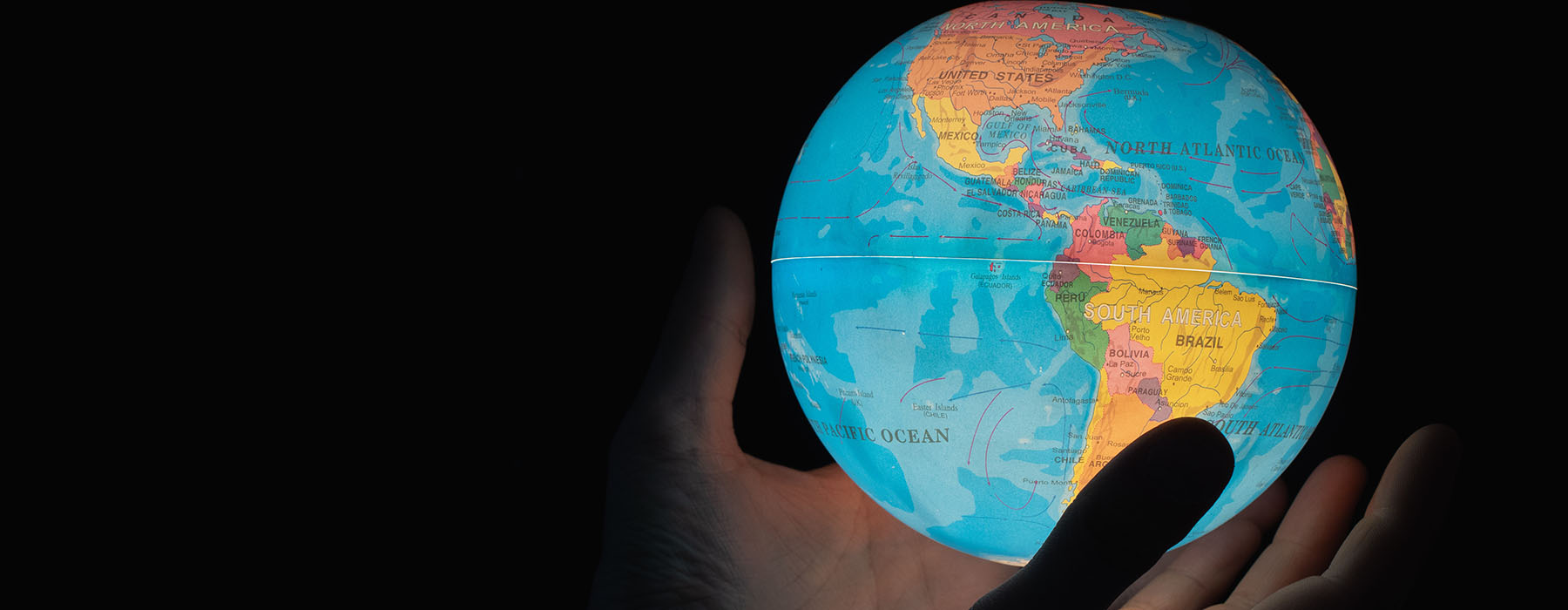 Photo of hands holding a small globe which is illuminated from the inside