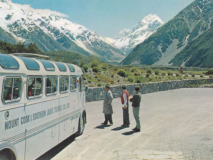 Mount Cook and bus, 1960s, by Gladys Goodall. Te Papa (PS.003574) View of Mount Cook from a carpark. A bus can be seen to the left and three people on the right stand looking at the mountain