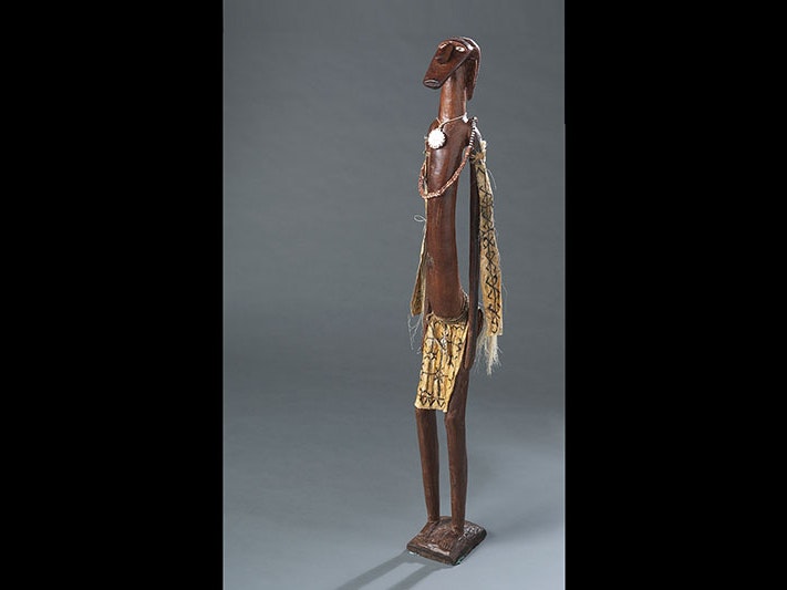 'Menepo', by David Kio, 2001, Solomon Islands. Purchased 2003. Te Papa (FE011760) A carved wooden figure with a necklace and breastplate and cloth with designs on it.