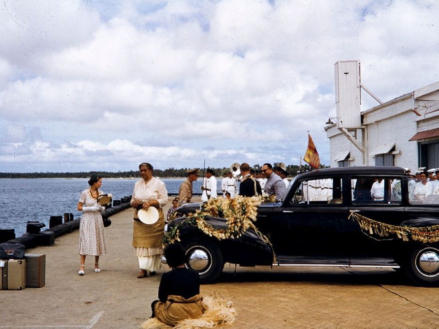 Queen Elizabeth II and Queen Sālote Tupou III, Royal Tour, Tonga. Brian Brake; photographer; 1953; Tonga. Gift of Mr Raymond Wai-Man Lau, 2001. Te Papa (CT.045203) A photo of the British Queen and the Tongan queen walking on a waterfront. There is a ceremonial car parked nearby.