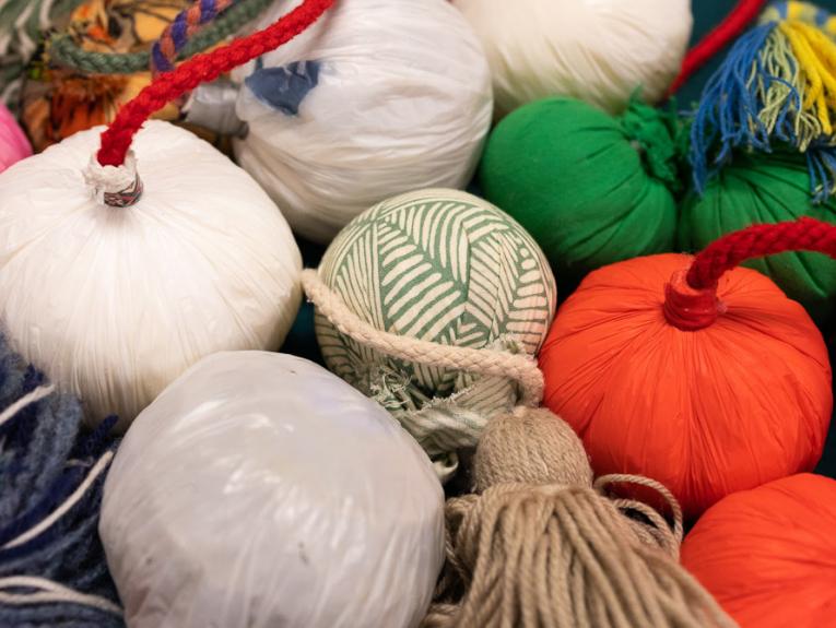 A group of brightly-coloured round balls with cords attached all clustered together.