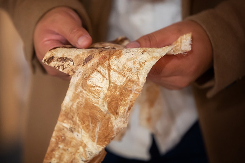 A close-up of a pair of hands holding a piece of tapa cloth.