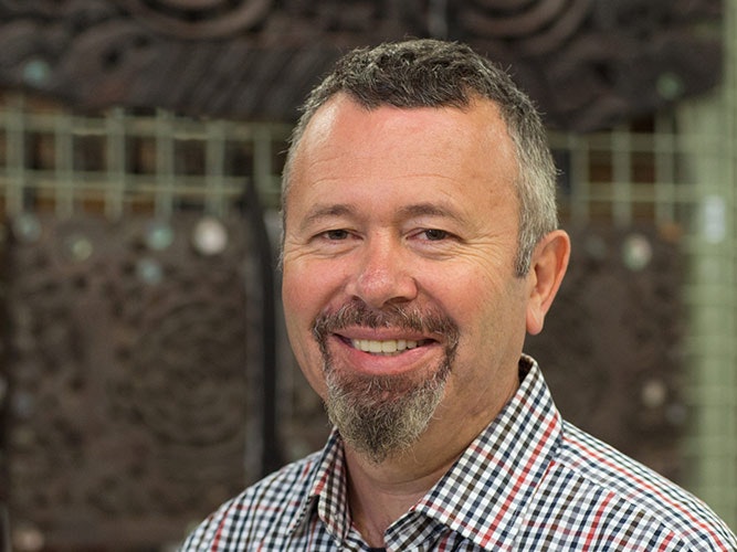 Dougal Austin, 2014. Photograph by Norm Heke. Te Papa Head and shoulders of a man with a goatee beard. He is smiling at the camera.