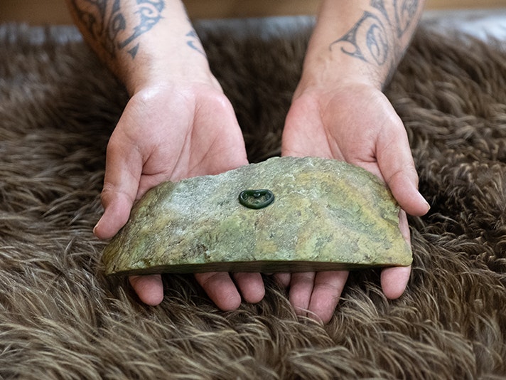 Pounamu master Te Tohu pin on pounamu, 2018. Photo by Rachael Hockridge. Te Papa (125955) Twp hands holding a large piece of pounamu