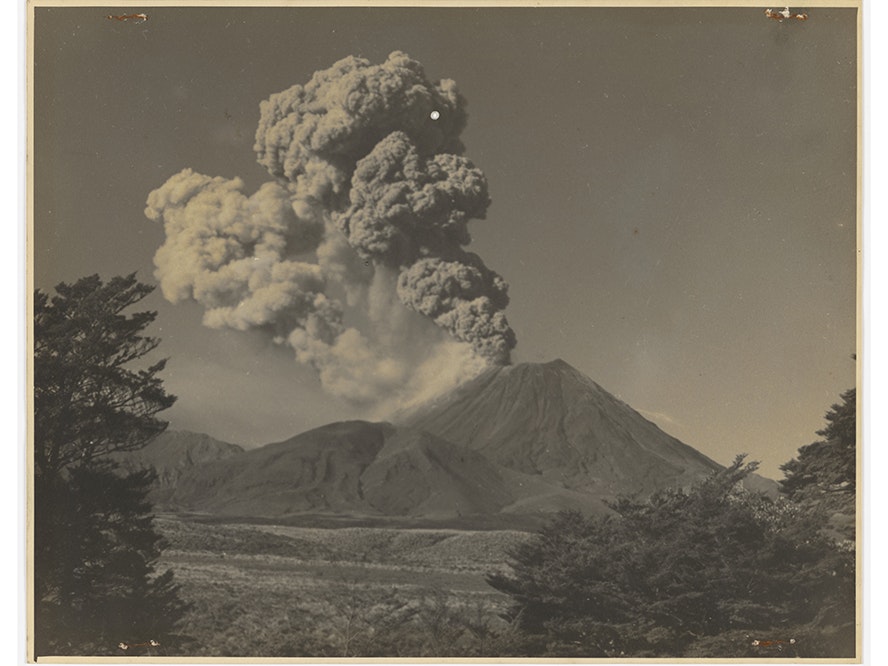 Ngauruhoe eruption, circa 1910, New Zealand, by Frederick Bunting. Purchased 1999 with New Zealand Lottery Grants Board funds. Te Papa (O.020948) A black and white photo of a massive amount of smoke coming out of the top of a mountain.