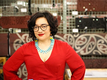 Photo by Jack Fisher. Te Papa Head an shoulders of a woman in a red dress who is smiling at the camera