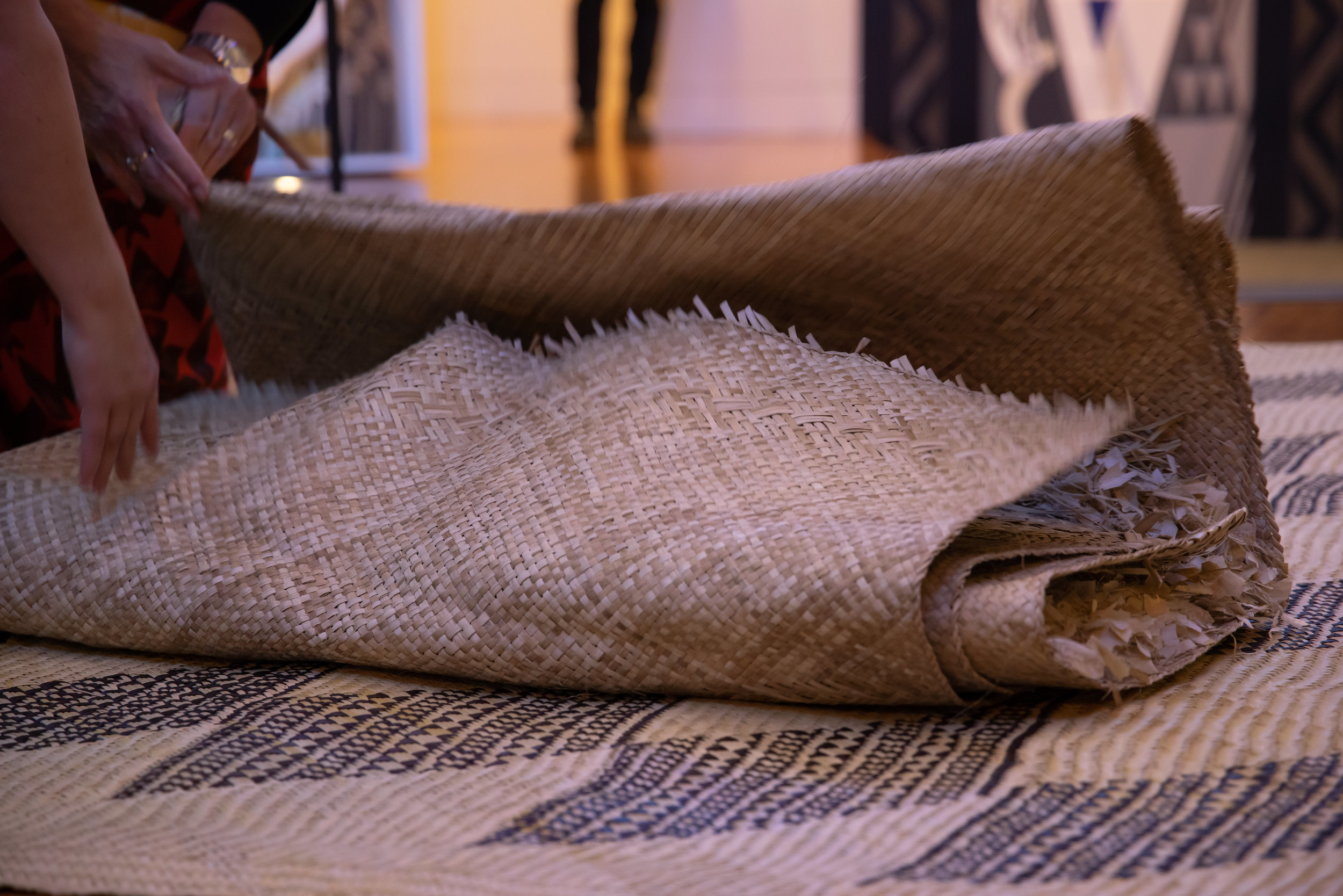 A woven mat lies on the ground on top of another woven mat.