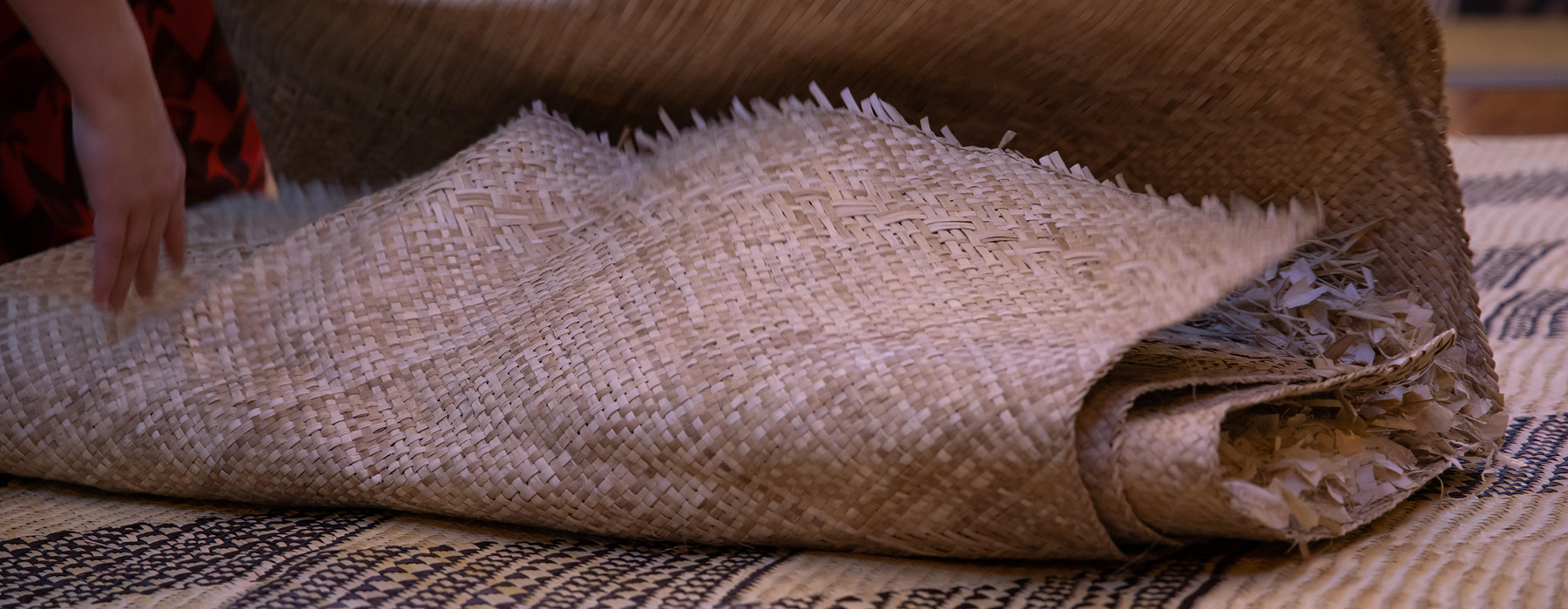 A woven mat lies on the ground on top of another woven mat.