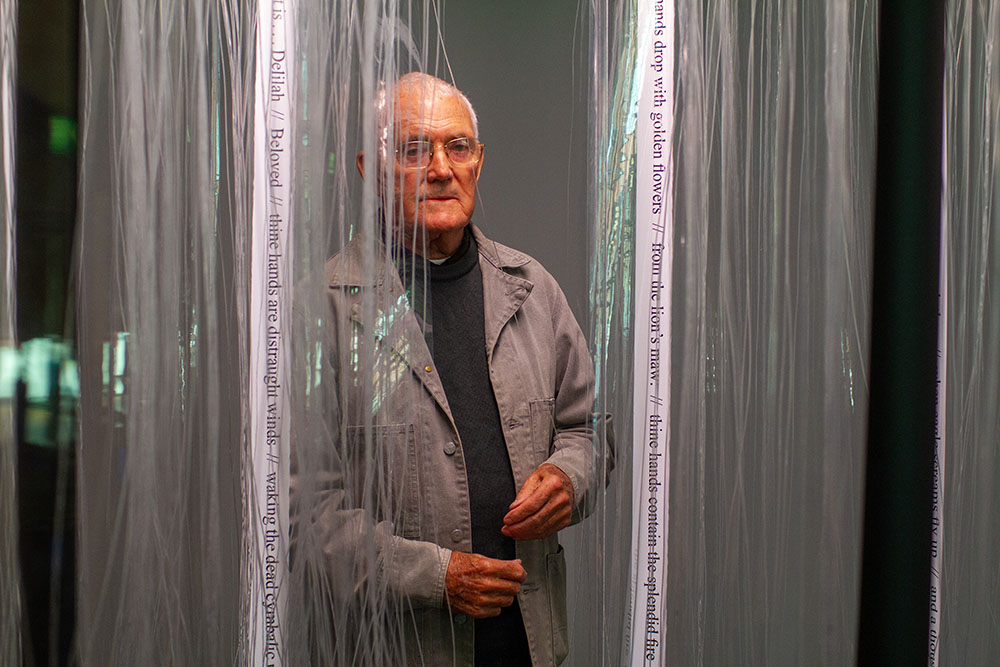 A man standing behind transparent curtains.