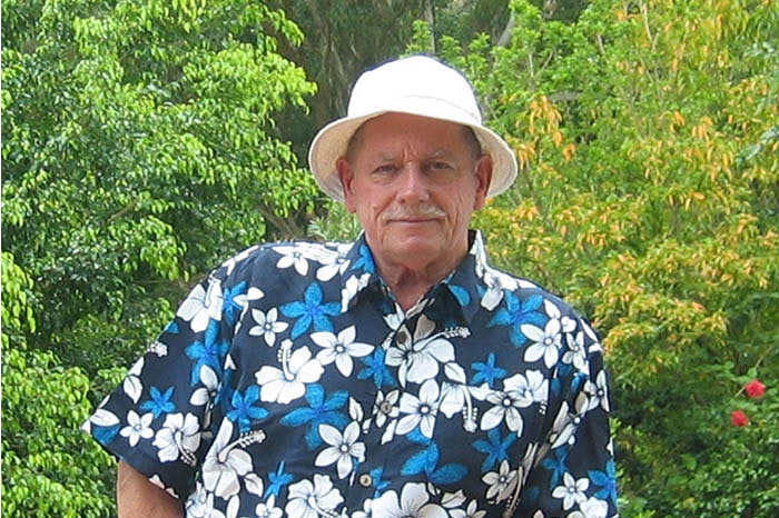 A man in a white hat and a blue and white floral shirt.