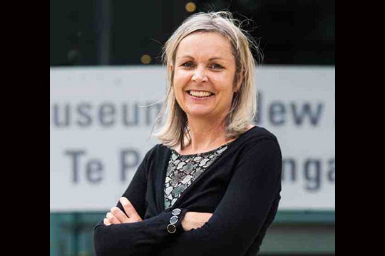 Photo of a woman with her arms crossed and smiling at the camera