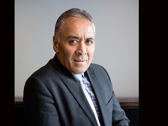 Monty Soutar A photo of a man in a suit leaning one arm on a table and looking at the camera