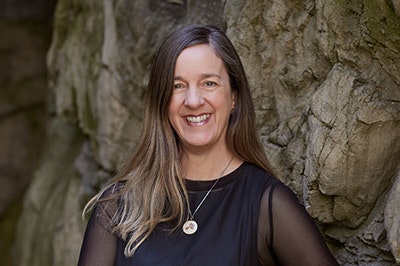 Head and shoulders of a woman with long hair smiling at the camera