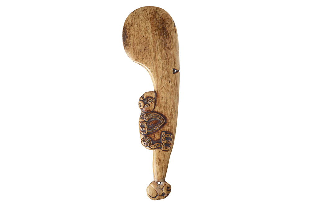 A whalebone club with a carving of a being on the handle.