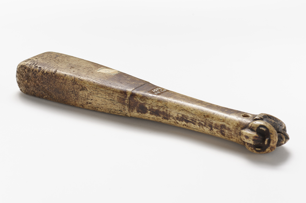 An aged brown mallet with detail carved on the end.