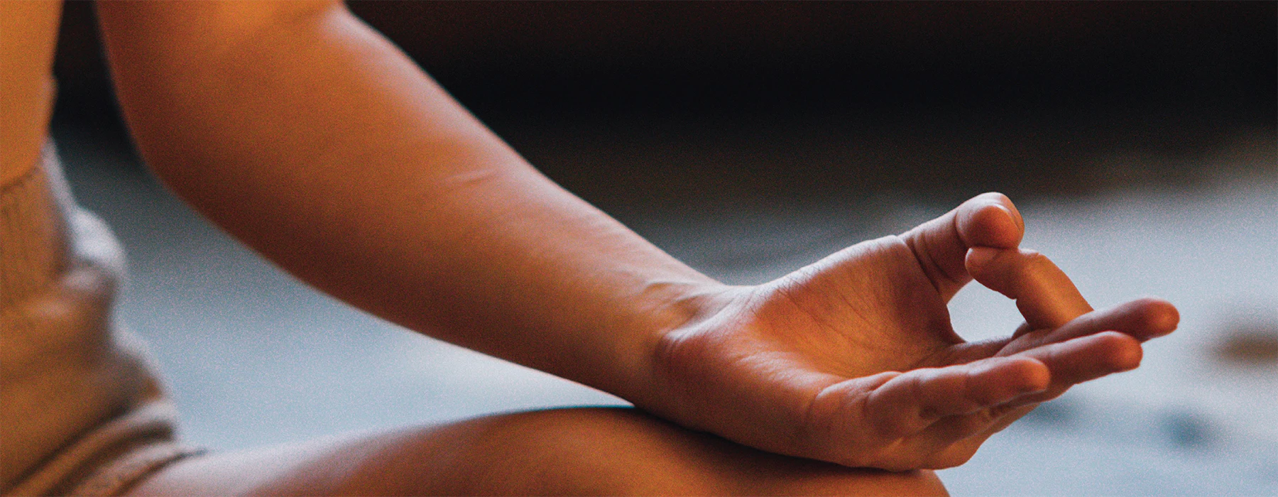 A close-up image of a hand in a yoga post resting on a bare knee.