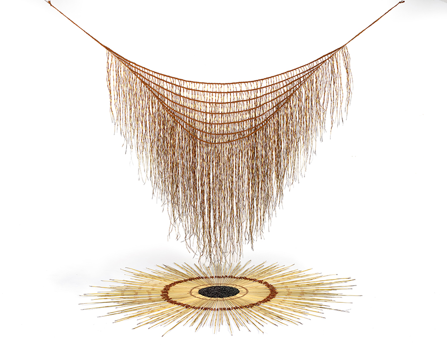 A woven shawl with long tassels is hanging over a circular-patterned spot made of flax and nylon.