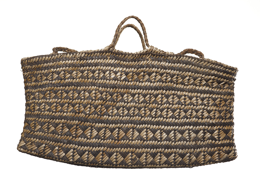 A woven bag or kete with two handles. There iare patterns woven into the sides.