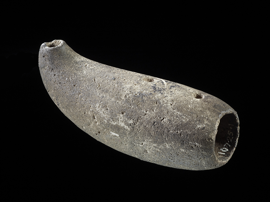 A small carved stone instrument with a large hole at one end, a small hole at the other and a couple of small holes on the top. It is blown with the nose as an instrument.