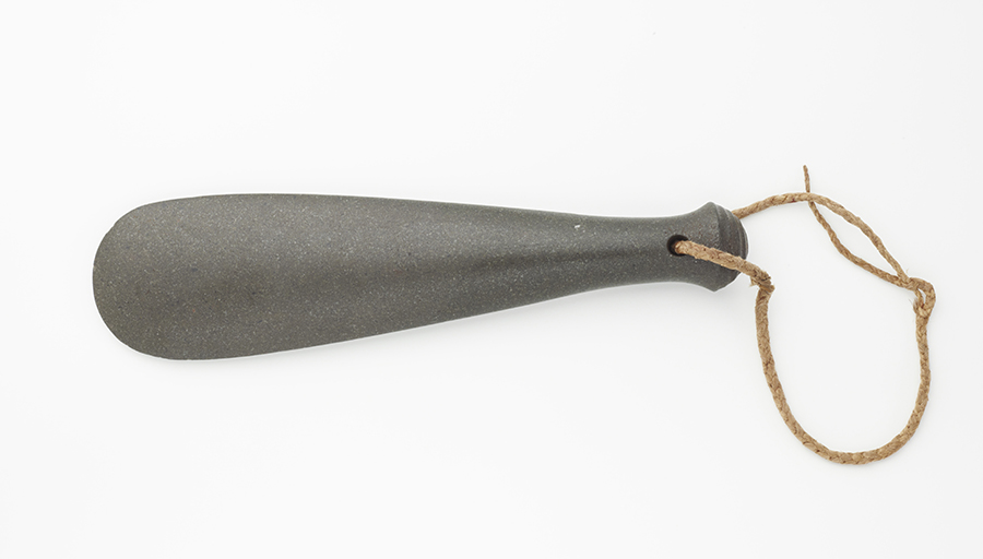 A long flat rounded stone club with a muka (flax) cord attacehd at one end,