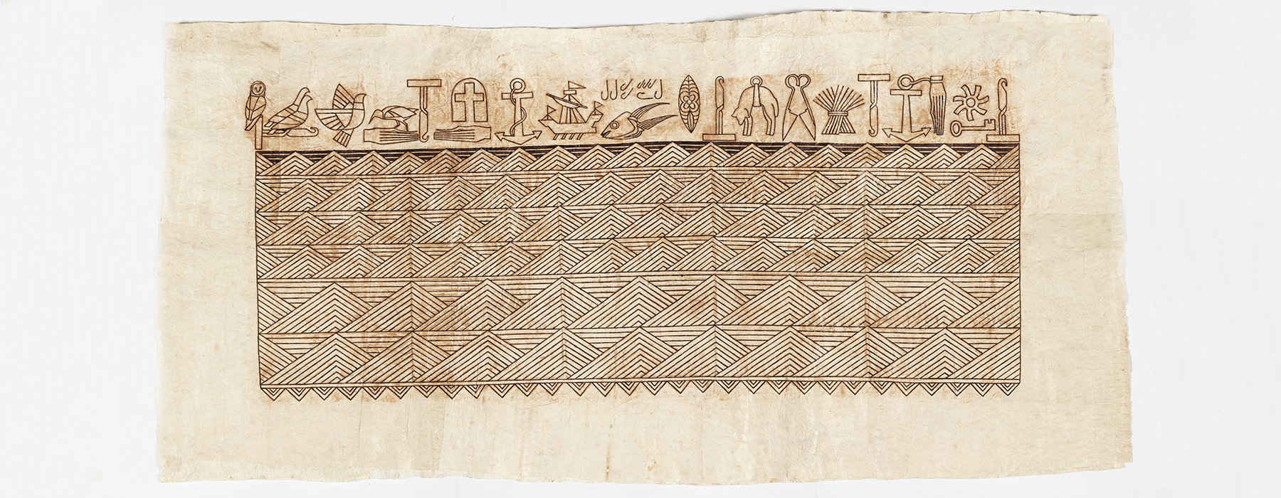 A long tapa cloth with patterns on most of it and a line of farm symbols, birds, anchors, and religious icons along the top.