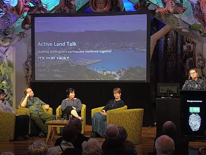 Still from livestreamed talk. Te Papa Four people on a stage with a large screen behind them.
