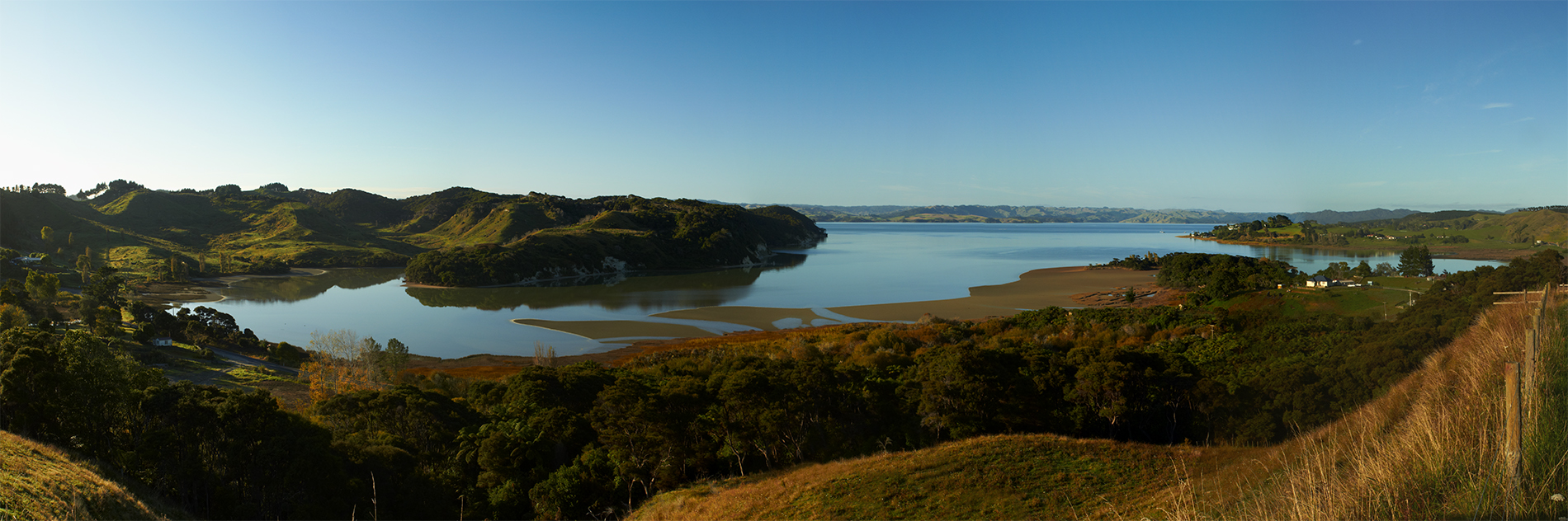 A panoramic photo of a still harbour and low-lying hills