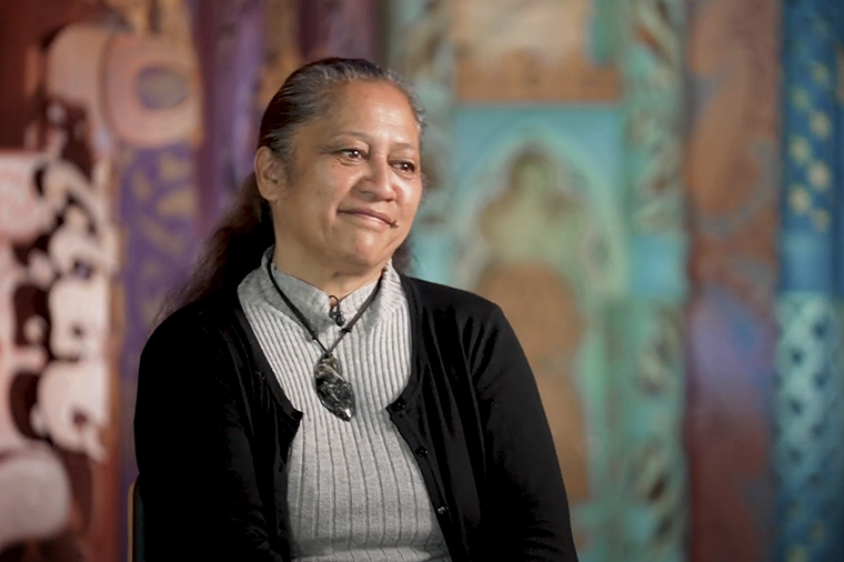 The head and shoulders of a woman smiling gently at someone off camera.