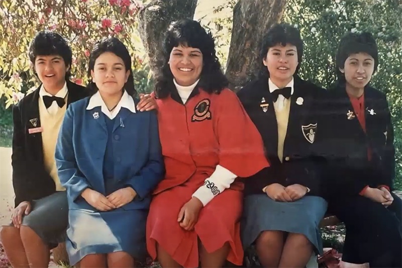 Five young schoolgirls are sitting under a tree,