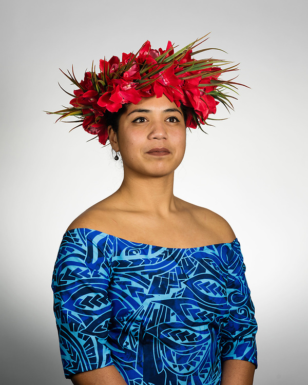 A portrait photo of woman wearing a floral headdress and a blue dress.