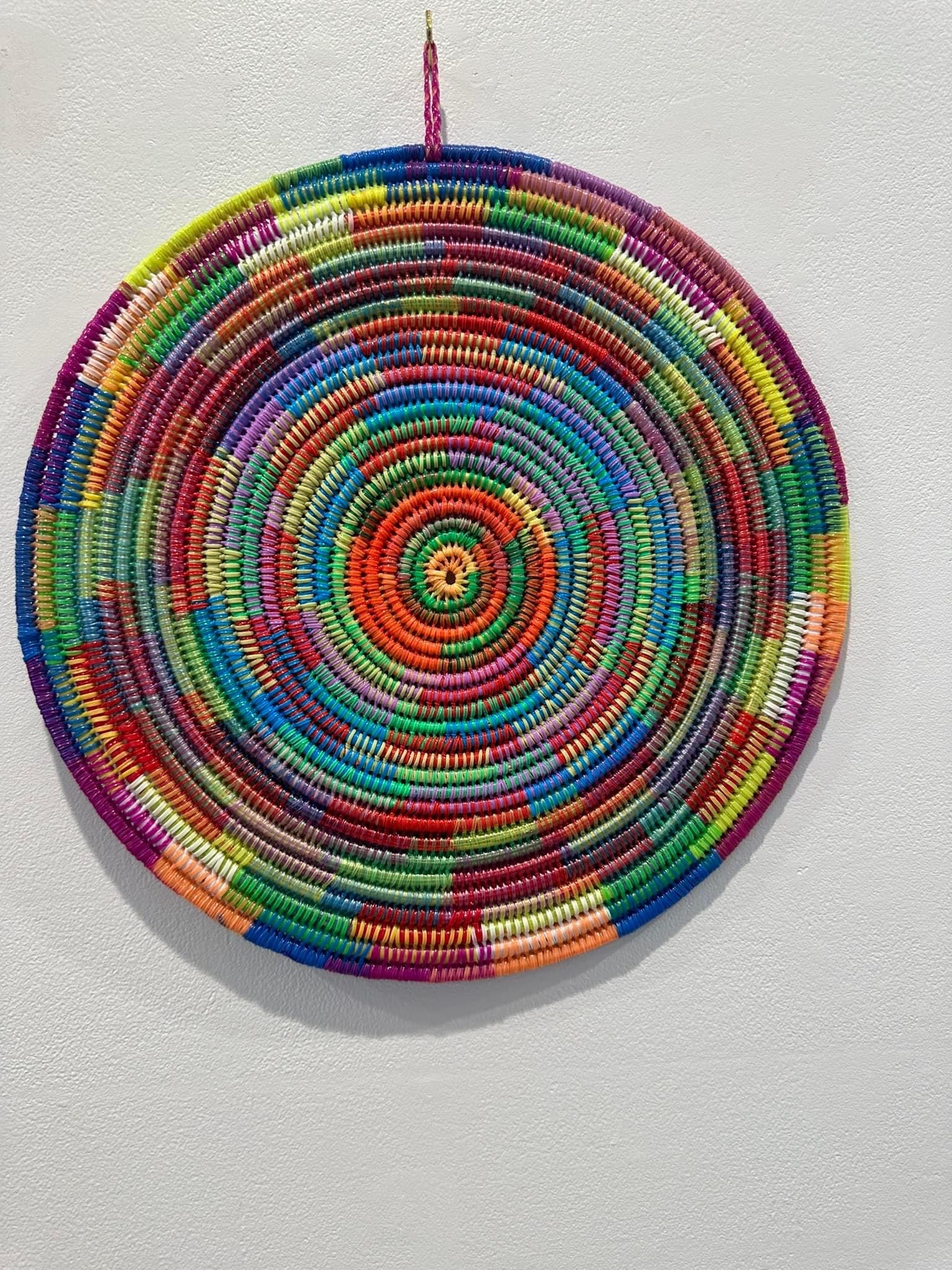 A colourful woven mat hanging on a wall.