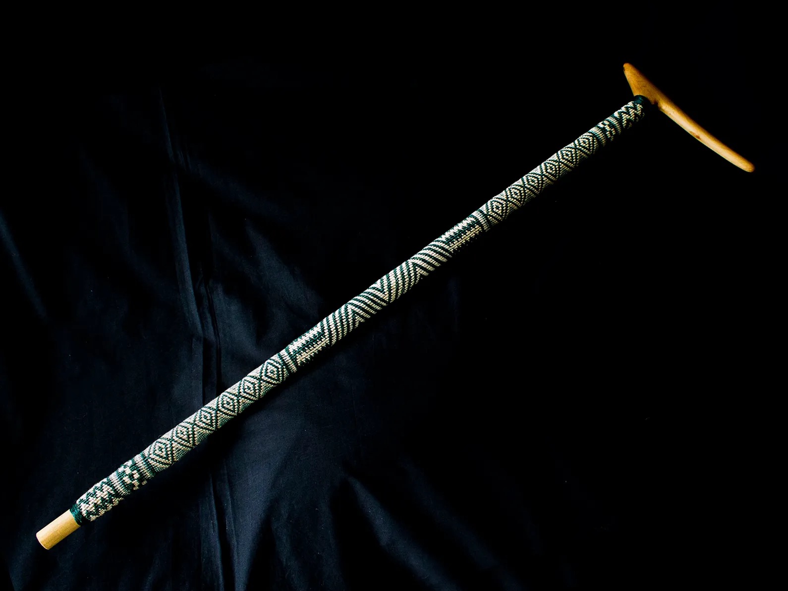 A walking stick with a woven cover on the shaft.