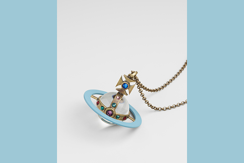 A pendant resembling a planet with a blue ring, gold details, and multicolored gems, hanging from a gold chain.