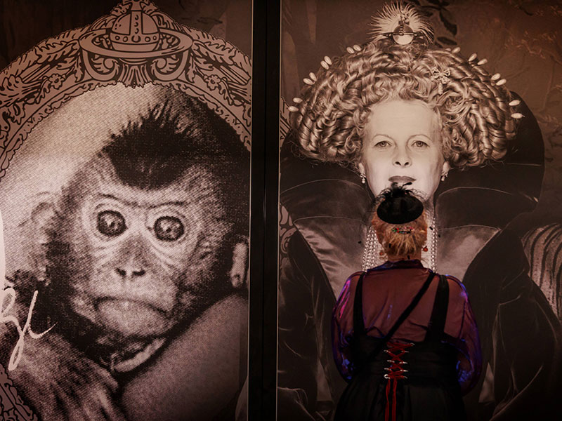 Photograph of a Te Papa visitor gazing at a mural featuring a monkey and Vivienne Westwood, her hair styled like royalty.