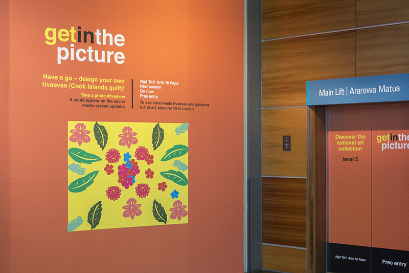 An installation photo of a promotion of an exhibition called Get in the Picture. It's a poster next to an elevator door.