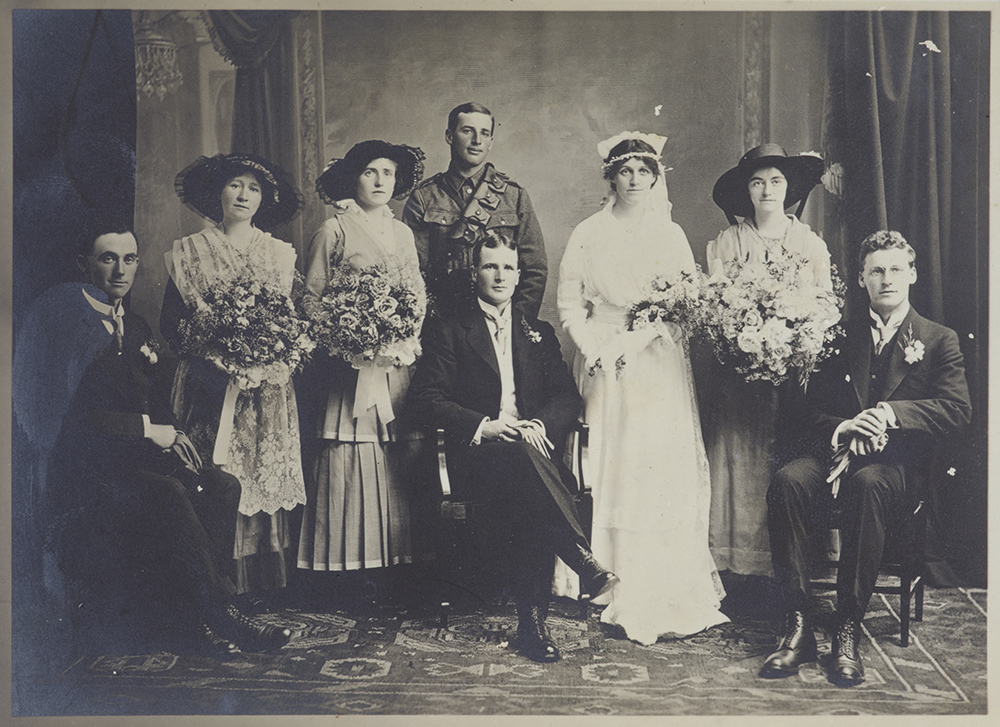 A black and white studio photo of a wedding party from 1915.