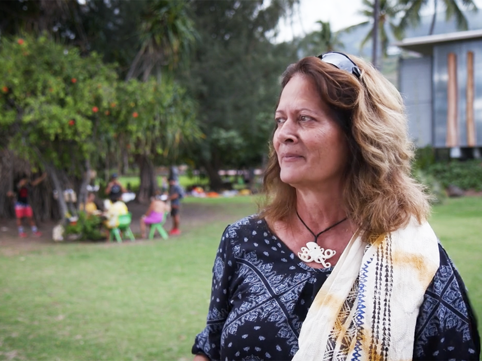 Still from video of Dalani Tanahy interview. Te Papa A woman with long hair is standing outside and looking off into the distance.