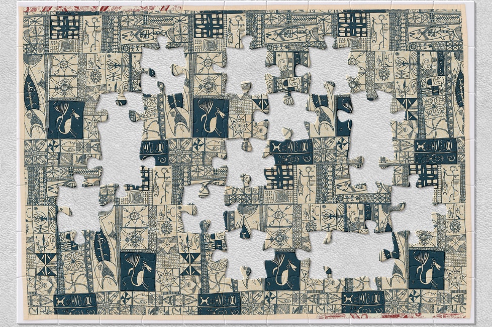 A cloth bed cover with blue and white patterns and designs stamped on it. There are jigsaw-shaped pieces missing from the image.