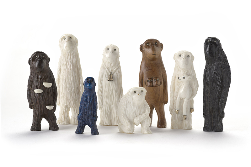 Eight ape-like figurines are standing or kneeling in a group on a white surface.