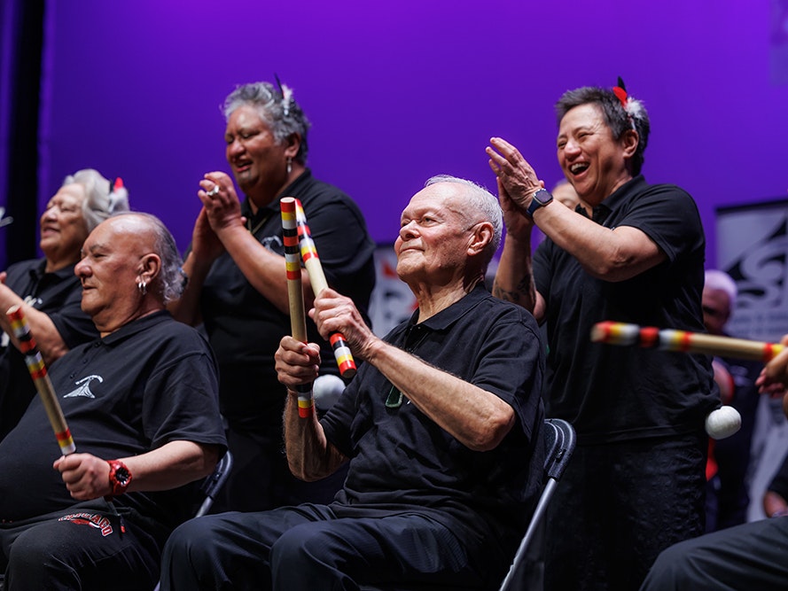 Te Upoko o Te Ika-a-Maui Taikura. Photo by Jo Moore. Te Papa (259202) Men and women singing and performing on a stage.