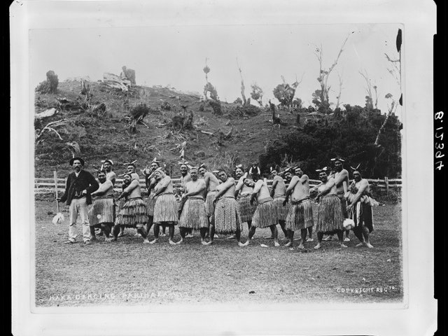 Haka party at Parihaka, circa 1885, Taranaki, by William Andrews Collis, Frederick Butler. F B Butler/Crown Studios Collection. Gift of Frederick B Butler, 1972. Te Papa (B.012394) Black and white historical photo of a haka party.