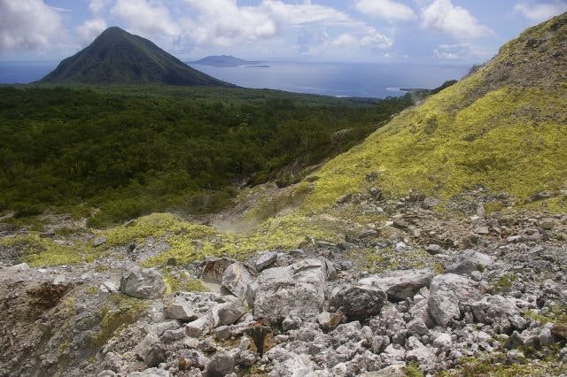 A mountain in the distance with the sea in the far distance.