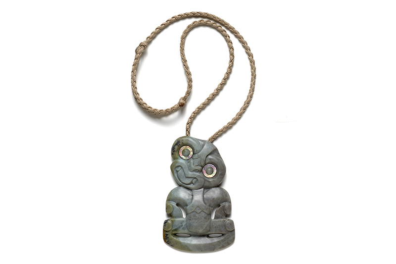 A pounamu or New Zealand Greenstone pendant in human form with a woven cord.