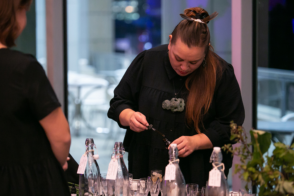A woman is putting something in a small bottle with a small dropper.