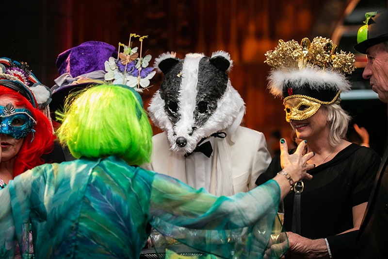 People dressed in costume and masks at a large party.