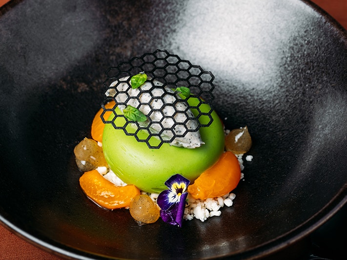 Tākina Events plated dessert, 2024. Photo by Anna Briggs. Te Papa (263541) A dessert in a large dark bowl.