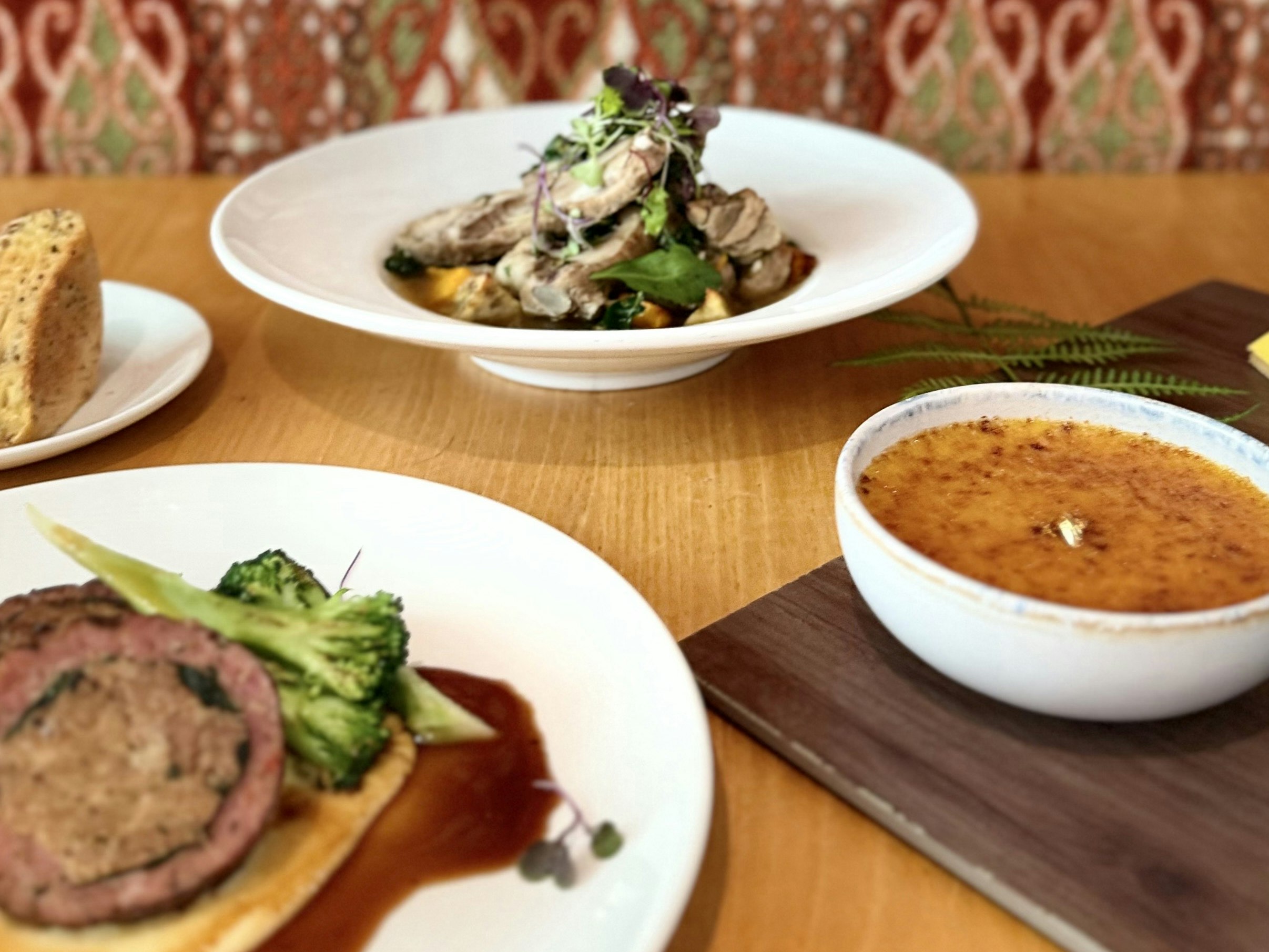 Kai Māori at Te Papa Cafe, November 2025. Photo by Caitlin Dorrington. Te Papa Plates of food on a table. Two are savoury dishes, one is sliced bread, and one is a bowl of dessert.