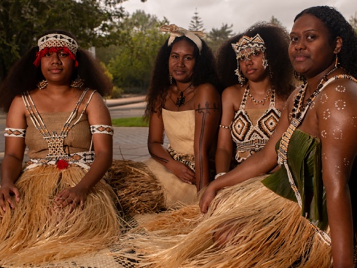 Crop from Ministry of Pacific Peoples Language Week resources Four women in Solomon Islands dress are sitting on woven mats.